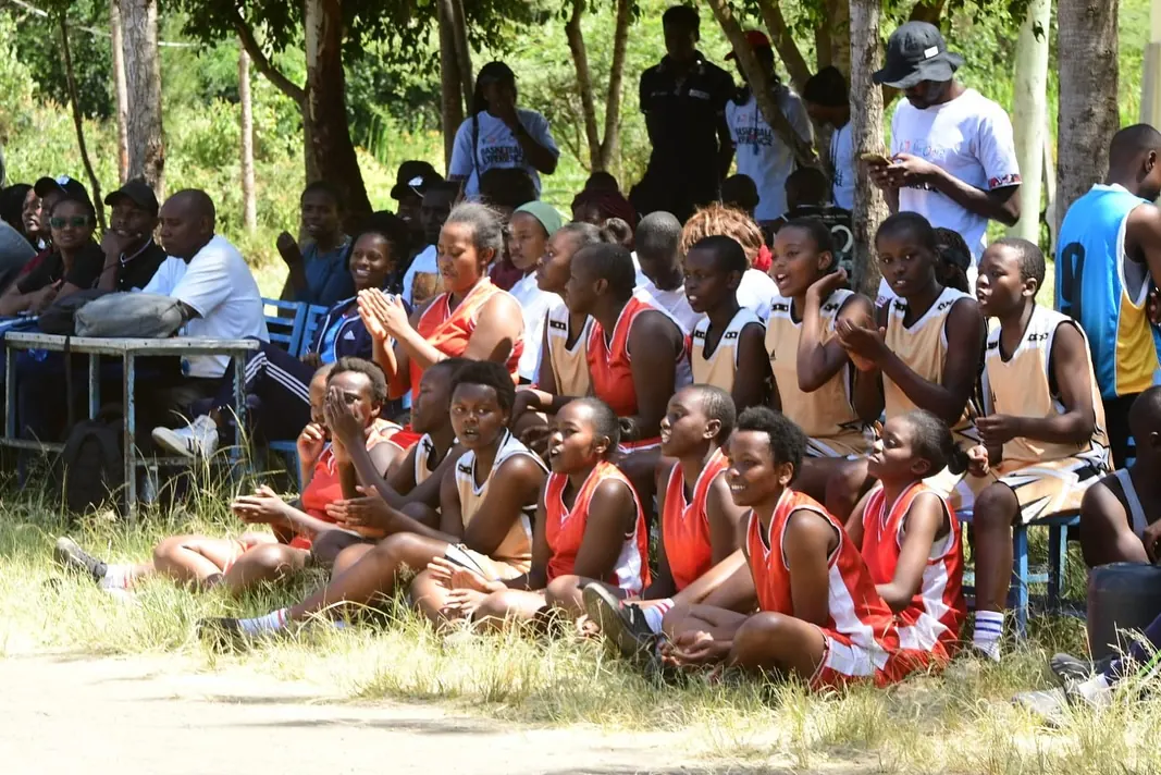 Girls' teams in team kit seated together at a Tala Opens fixture with supervising adults present